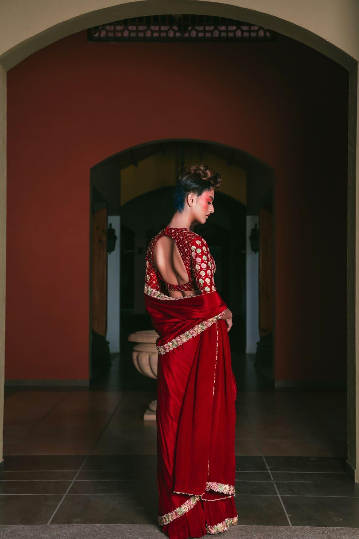 Red velvet blouse with antique gold zari embroidery, worn with a red saree