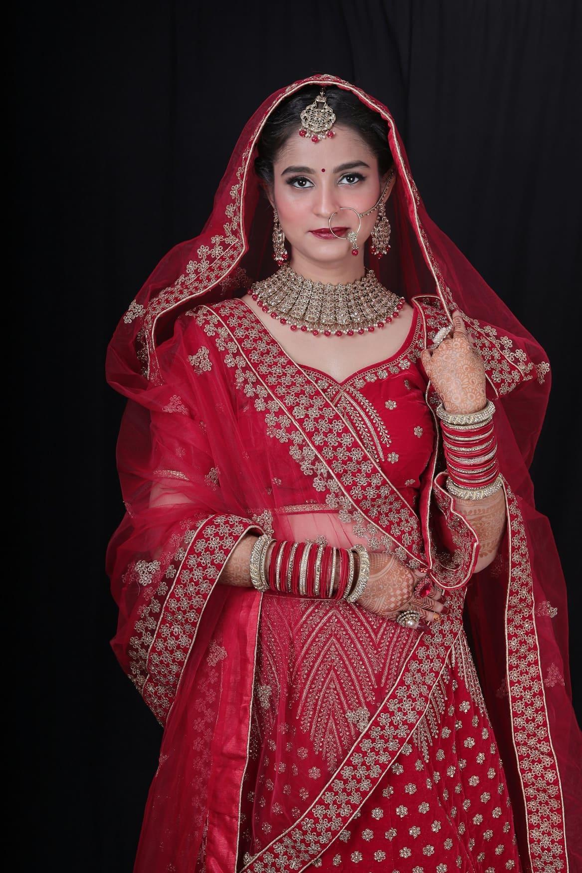 Bride in a red lehenga with heavy gold zari embroidery and a red net dupatta